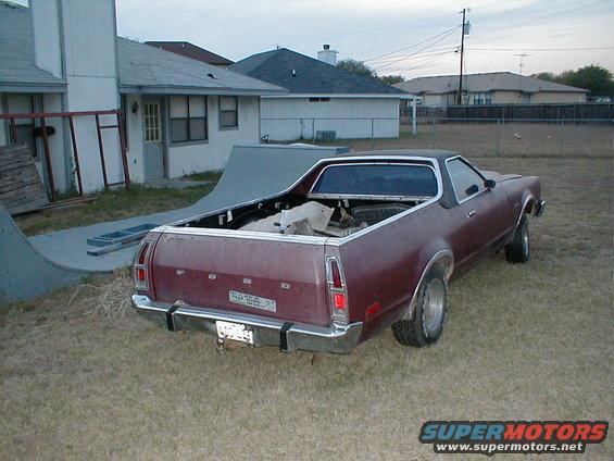 Maroon Ford Ranchero parked in a grassy yard with a skate ramp nearby