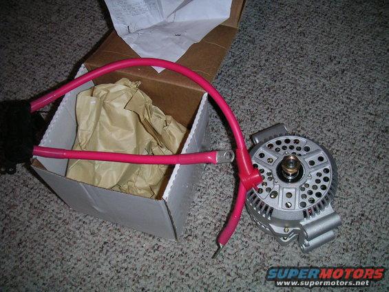 New alternator with red battery cables next to an open box