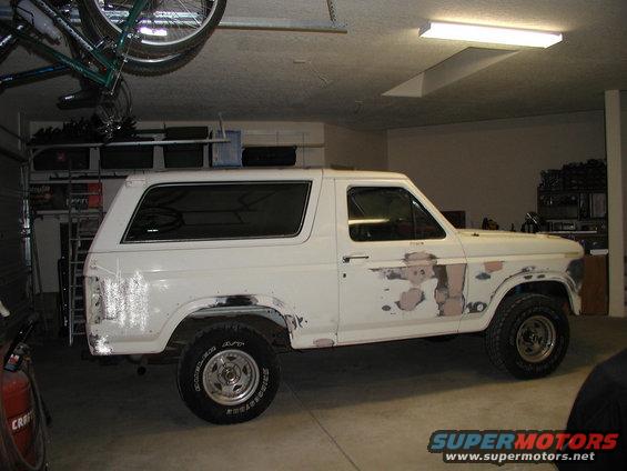White 1986 Ford Bronco parked indoors, side view. Decals on the door