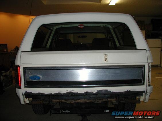 1986 Ford Bronco rear view, white body with dark blue/black trim panel between taillights