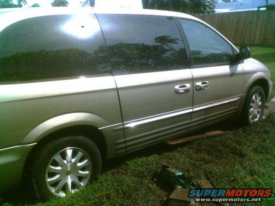 Side view of a tan minivan parked on grass