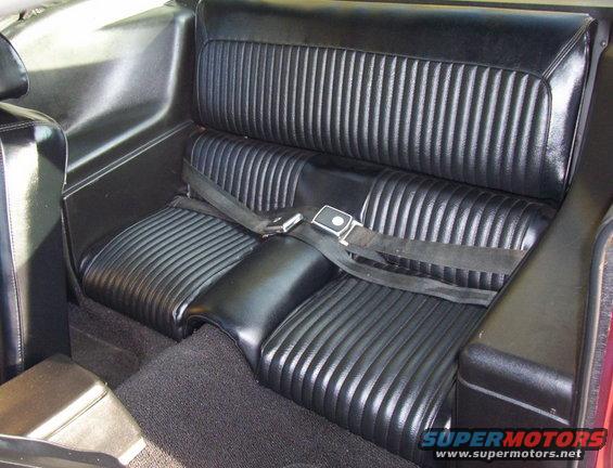 Back seat with black vinyl ribbed upholstery and seatbelts