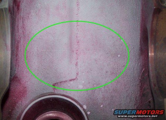 Engine part with red dye penetrant showing a crack circled in green