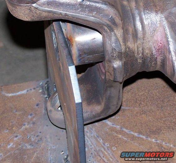 Close-up of a metal part being welded, showing a sharp edge and a threaded bolt