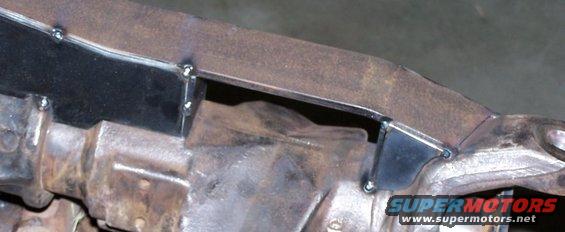 Close-up of rusty vehicle frame with welded metal brackets and drivetrain components