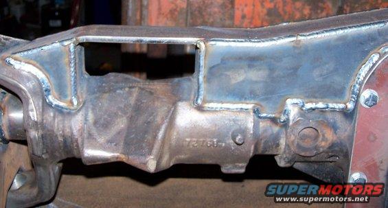 Close-up of a welded metal vehicle frame part with a stamped number