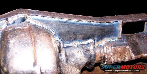 Close-up of a heavily welded metal frame component with visible rust and discoloration