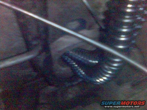 Close-up of a coiled suspension spring and a metal rod, likely from a vehicle's undercarriage