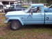 1985 Jeep Grand Wagoneer - Side view of a light blue Jeep Comanche pickup truck with a dark pickup truck behind it.