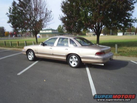 Tan sedan parked in a parking lot, side view