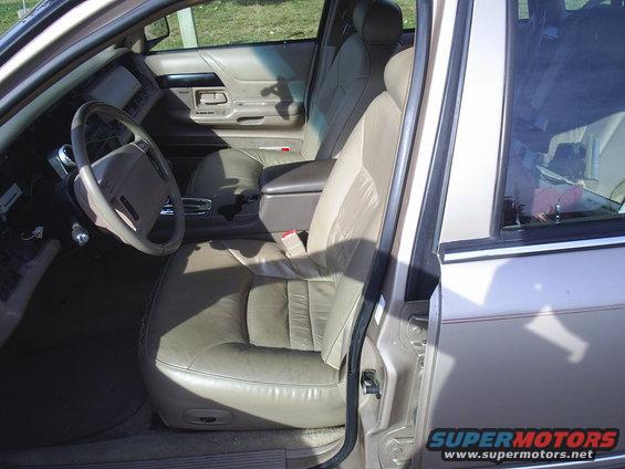 Tan leather interior of a 1990s sedan, showing front seats, dashboard, and door panel