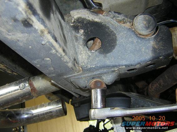 socket wrench on bolt on vehicle frame, exhaust pipe visible