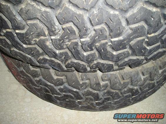 two stacked, worn off-road tires with aggressive tread pattern
