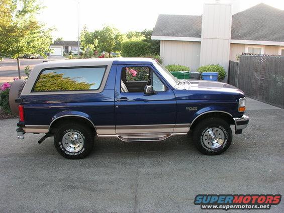 Blue 1996 Ford Bronco with tan trim and a spare tire on the rear, parked on a driveway
