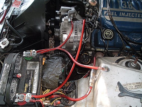 Engine bay showing battery, alternator, and "3.8 FUEL INJECTED" engine cover