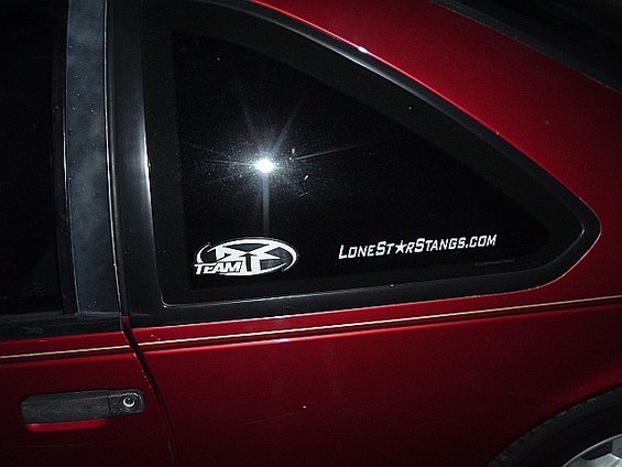 Red car's rear quarter window shows a 'TEAM' logo and 'LoneStarStangs.com' sticker