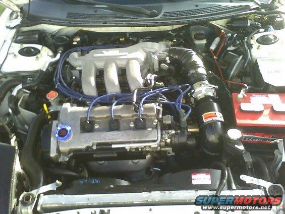 1996 Ford Probe engine bay with V6 engine, blue spark plug wires, and aftermarket air intake