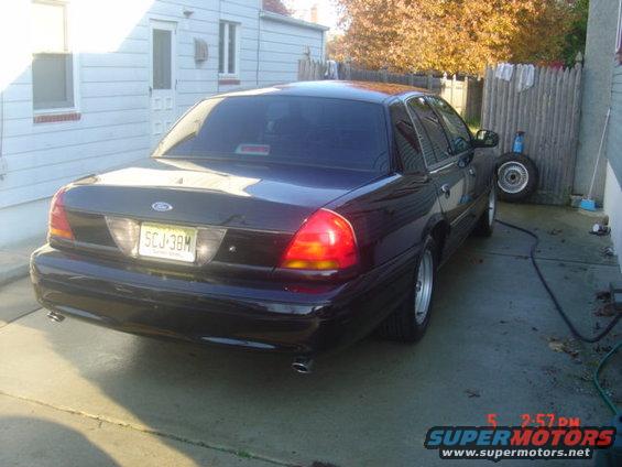 Dark Ford Crown Victoria parked in driveway, rear view. License plate SCJ-38M