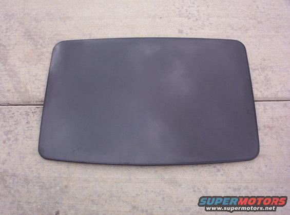 Dark gray car roof panel with rounded corners, lying flat on a concrete surface