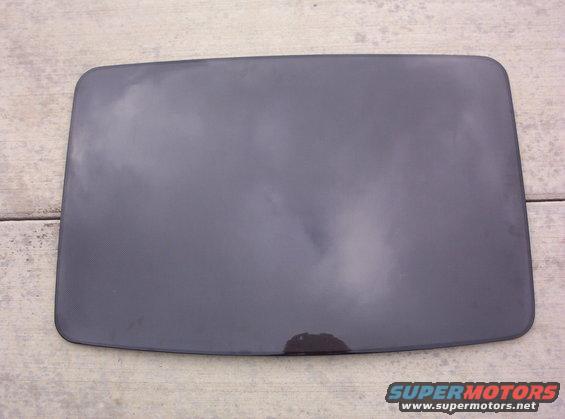 Dark gray car part with a stain on a wooden surface