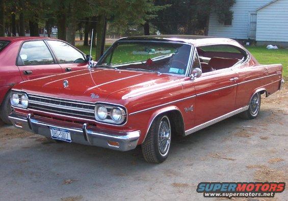 Red 1967 AMC Rambler American coupe parked next to a dark red sedan