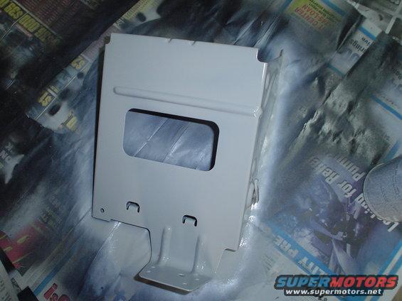 White metal bracket with a rectangular cutout, resting on newspaper