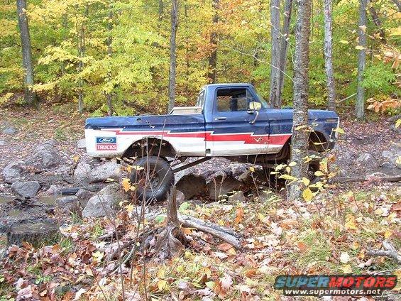Blue and red Ford F-Series truck with lifted suspension on rocks