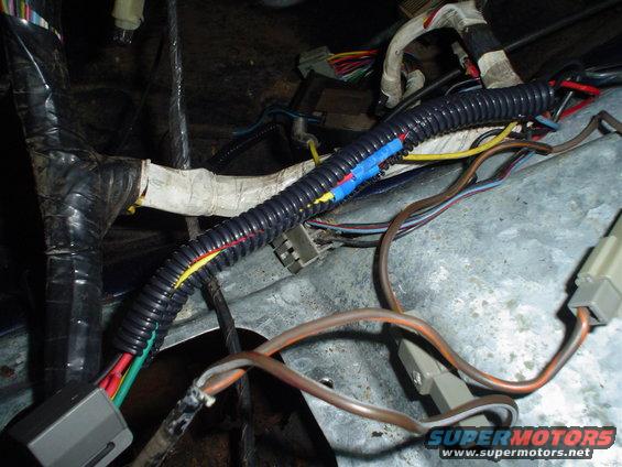 Close-up of a vehicle's wiring harness with black protective conduit and various colored wires
