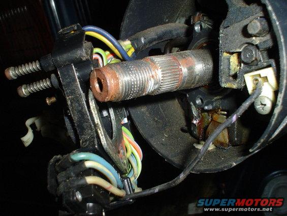Close-up of a rusty steering column shaft and electrical connectors with colorful wires