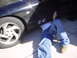 1993 Ford Probe - A person works on the underside of a black 1993 Ford Probe, visible from the side.