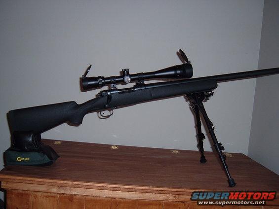 Rifle with scope and bipod on a wooden surface