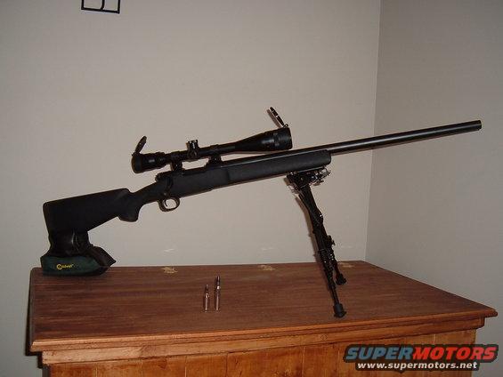 Rifle with scope and bipod on wooden surface