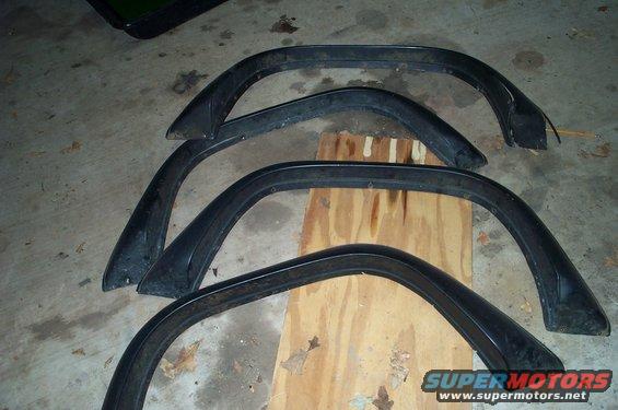 Four black fender flares on a wooden board