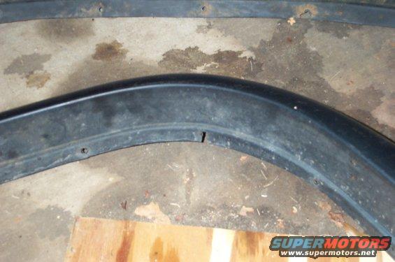 Black plastic fender trim piece with visible mounting holes and a small crack
