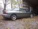 1996 Ford Probe - A gray coupe sits on a gravel surface next to a shed and a barn with equipment inside.