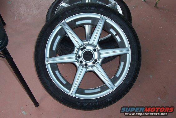 Two alloy wheels with tires stacked, one in foreground