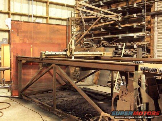 industrial welding machine in workshop with metal stock on shelves