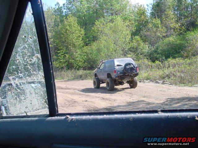 SUV with spare tire on back driving on dirt road