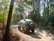 1992 Chevrolet S10 - A man stands atop a black Chevrolet K5 Blazer as it navigates a dirt trail through a wooded area.