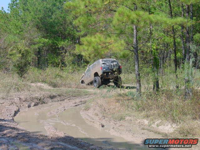 Off-road vehicle with rear facing camera stuck in a muddy rut on a dirt track