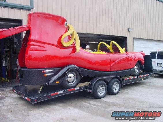 Red novelty car shaped like a boot on a trailer, yellow interior accents