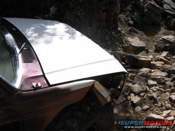 off-road vehicle with white hood on rocky terrain