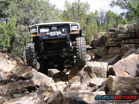 White off-road vehicle with large tires navigating a rocky terrain