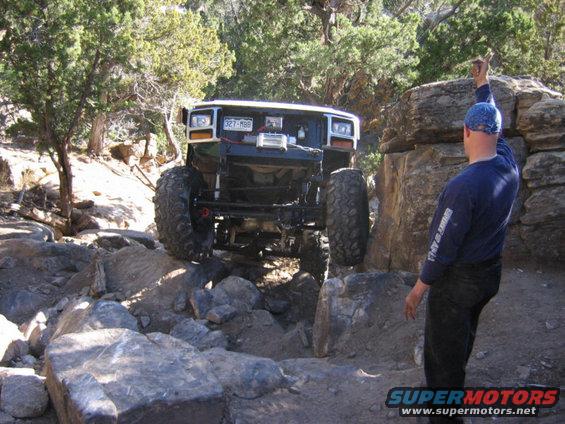Modified off-road vehicle with large tires navigating rocky terrain