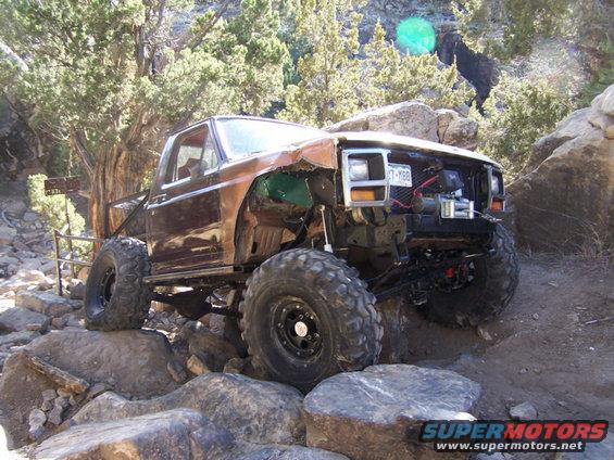 Brown off-road SUV with large tires navigating rocks. License plate reads 'T-Y88'