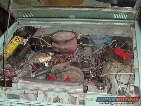 1969 Ford Bronco engine bay with V8 engine, air compressor tank, and yellow hose