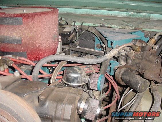 Engine bay with a large red air filter, hoses, and engine components. Some blue and black boxes are visible