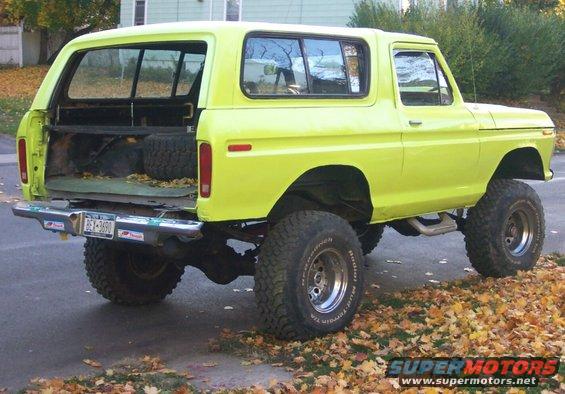 Yellow 1978 Ford Bronco with lifted suspension and off-road tires, rear view with tailgate down