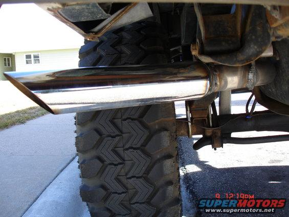 Close-up of a chrome exhaust pipe and large tire on a vehicle