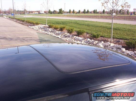 Black car sunroof with a carbon fiber pattern, viewed from above